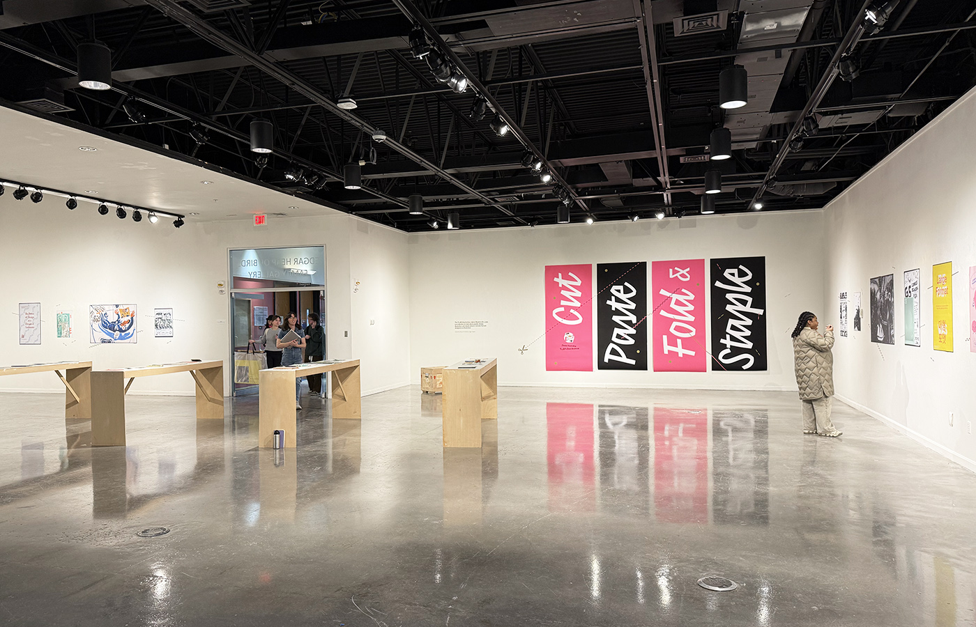 a view through gallery doors of an art exhibition featuring zines
